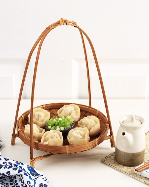 Dumpling Mandu al vapor, comida callejera tradicional coreana de dim sum. Servido en un plato de bambú con cebolleta picada y salsa de sal de soja