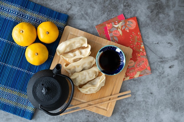 Foto dumpling con salsa en tablero de bambú y telón de fondo de mármol con decoración de año nuevo chino cocina asiática espacio de copia vista superior