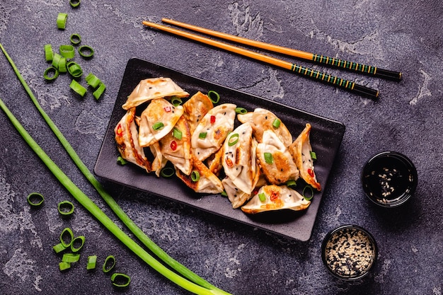 Dumplings fritos servidos con cebollas verdes semillas de sésamo y chiles