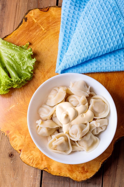 Dumplings en un plato blanco con ensalada sobre un fondo de madera