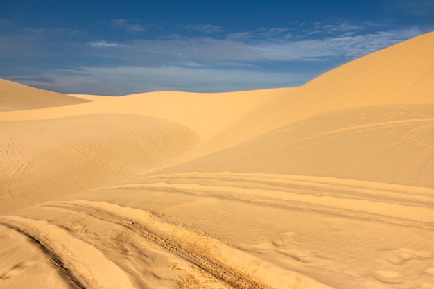 Duna de arena con la pista de la rueda y el fondo del cielo azul en Muine, Vietnam