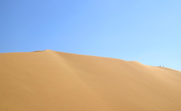 Duna de areia maciça do deserto de Huacachina com pessoas andando no topo na região de Ica, no Peru