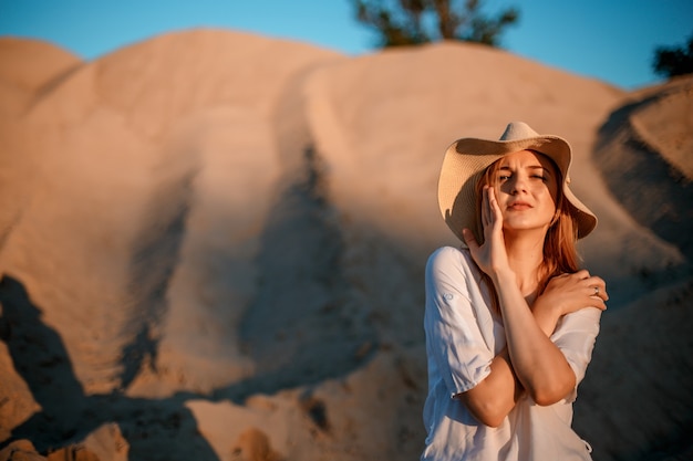 Dunas y líneas, paisaje escénico. Mujer joven sentada y contemplando las dunas. Viaje.