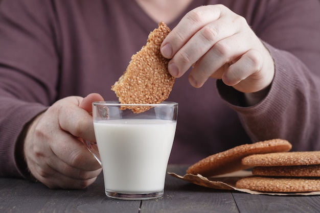 Dunk biscoitos de gergelim biscoitos no copo de leite na mesa