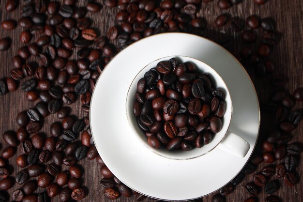 Dunkel geröstete Kaffeebohnen in weißer Tasse mit verschwommenen Kaffeeböhnen