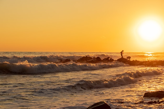 Dunkelblaue Wellen gegen den wunderschönen orangefarbenen Sonnenuntergang am Schwarzen Meer, Anapa, Russland