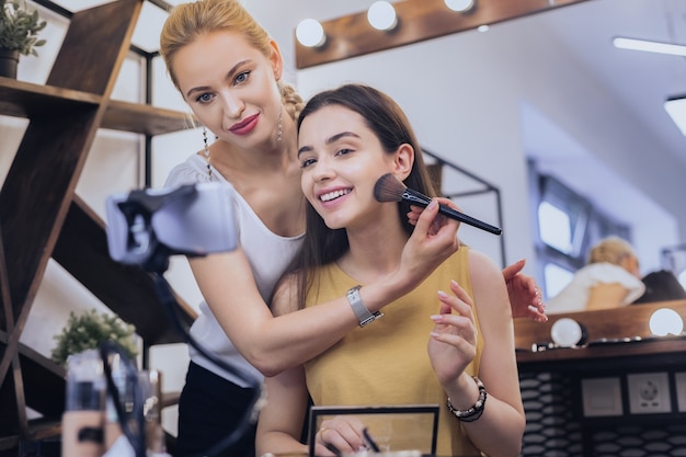 Dunkelhaarige Frau. Lächelnde dunkelhaarige Frau, die zum Schönheitssalon kommt, während sie schönes abendliches Make-up benötigt