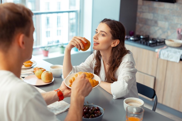 Dunkelhaariger Ehemann gibt Croissants für Frau, die Apfel isst