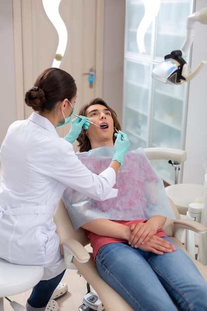Dunkelhaariger kaukasischer Teenager, der in einer Zahnarztpraxis sitzt