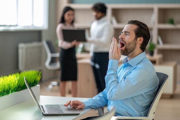 Dunkelhaariger Mann, der im Büro am Laptop arbeitet