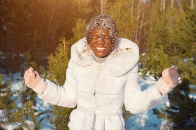 Dunkelhäutige Frau, die mit Schneesonnenlicht lacht.