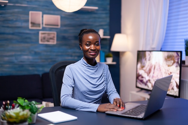 Dunkelhäutige geschäftsfrau, die ein digitales gerät verwendet, das spät nachts im home office arbeitet. schwarzer unternehmer, der am persönlichen arbeitsplatz sitzt und auf der tastatur schreibt.