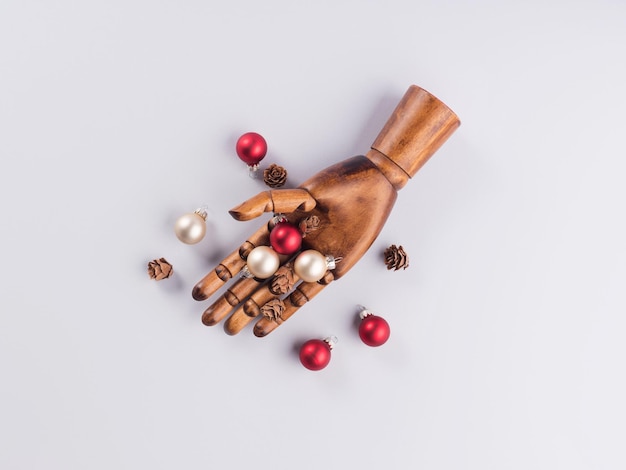 Dunkle Holzhand mit Weihnachtsbaumschmuck auf Grau