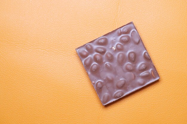Dunkle Schokolade mit Mandelnuss auf orangefarbenem Hintergrund