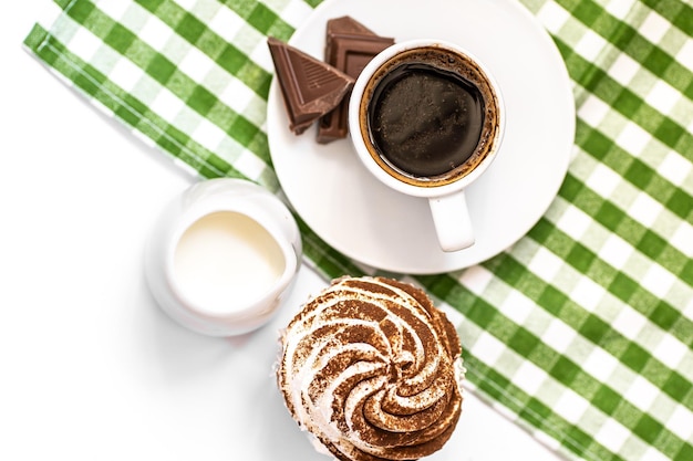 Dunkle Schokoladen- und Kakaoschokoladen-Cupcakes mit einer Tasse heißen schwarzen Kaffees auf grüner Serviette Platz für Text