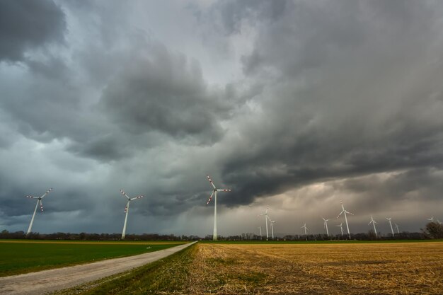 Dunkle schwarze Regenwolken mit vielen Windmühlen und einem Feldweg