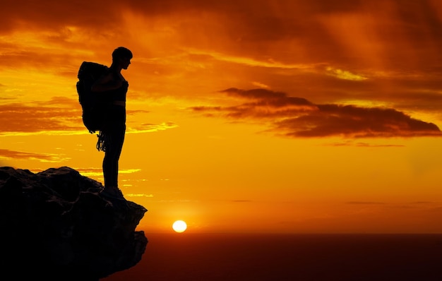 Dunkle Silhouette Bergreise und Sonnenuntergang beim Wanderabenteuer in der Natur Himmel orange beim Trekking mit Rucksack und Freiheit auf der Klippe Person im Urlaub in Afrika zu Fuß auf Sommerreise