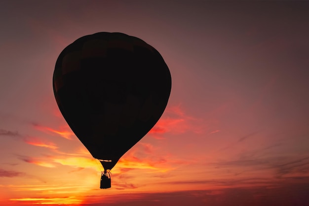 Dunkle Silhouette des Heißluftballons oder Aerostaten auf dem Hintergrund des farbenfrohen Sonnenuntergangs Romantik des Fluges