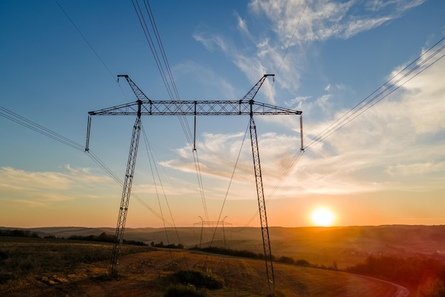 Dunkle Silhouette des Hochspannungsturms mit Stromleitungen bei Sonnenaufgang Übertragung des elektrischen Energiekonzepts