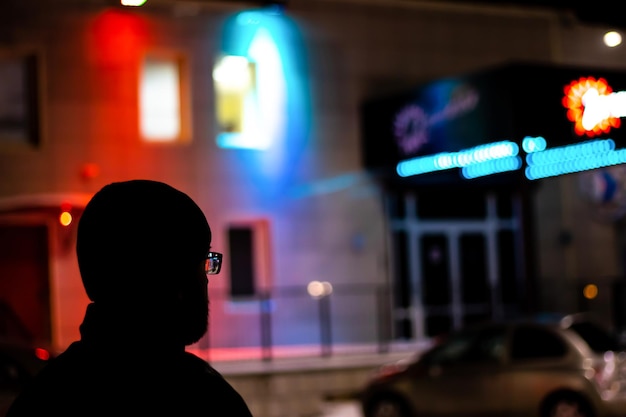 Foto dunkle silhouette des menschen auf dem hintergrund von neoninschriften beleuchtet nachts beleuchtete schilder