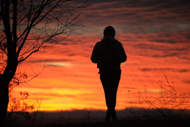 Dunkle Silhouette einer einsamen Frau, die den Blick auf den Sonnenuntergang in der abendlichen Natur genießt Einsamkeits- und Einsamkeitskonzept