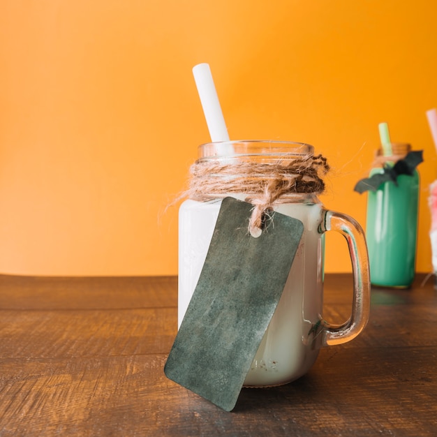 Dunkler Aufkleber auf Becher mit weißem Farbgetränk mit Stroh