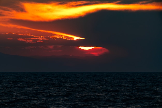 Dunkler dramatischer Sonnenuntergang über dem Meer