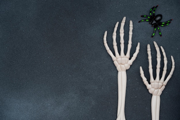 Dunkler Halloween-Hintergrund mit Skeletthänden und einer Spinne