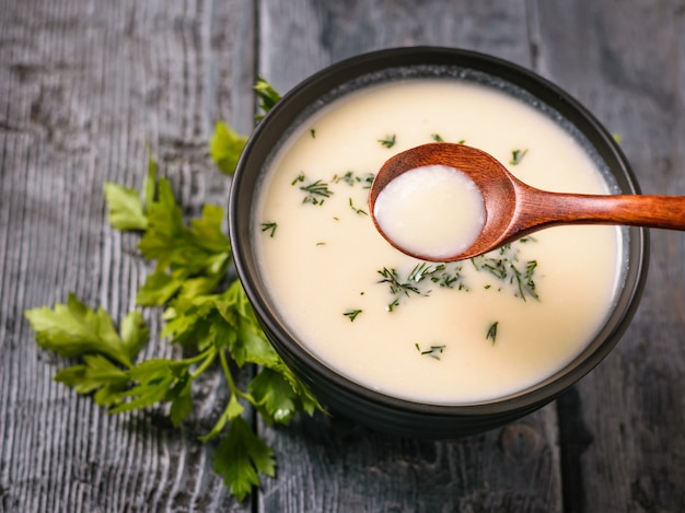 Dunkler Holzlöffel mit Blumenkohlpüreesuppe auf schwarzem Tisch