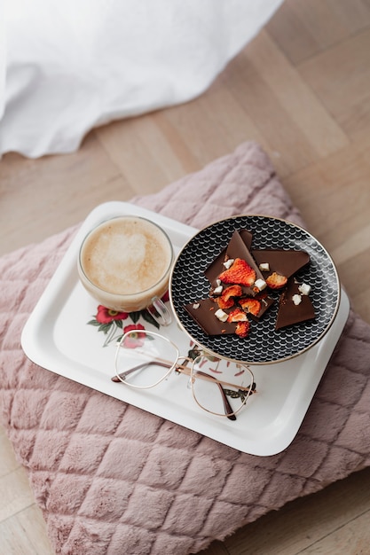 Dunkler Schokoladenkrokant mit Erdbeere diente mit Kaffee auf einem rosa Kissen