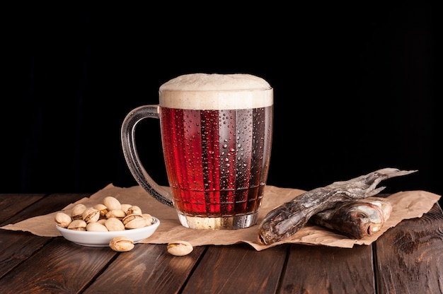 Dunkles kaltes Bier in einem frostigen Becher auf dunklem Holztisch