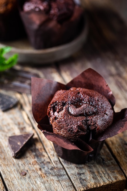 Dunkles Schokoladenmuffin mit Minze auf einem Holztisch hausgemachtes Backen