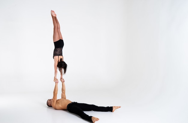 Duo de acrobatas masculinos e femininos mostrando truque corpo a corpo, isolado no branco