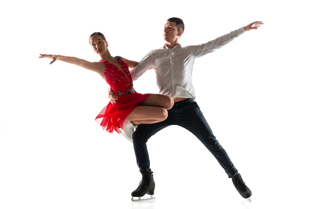 Foto duo de patinação artística isolado na parede branca do estúdio com copyspace. dois desportistas praticando e treinando em ação e movimento. cheio de graça e sem peso. conceito de movimento, esporte, beleza.