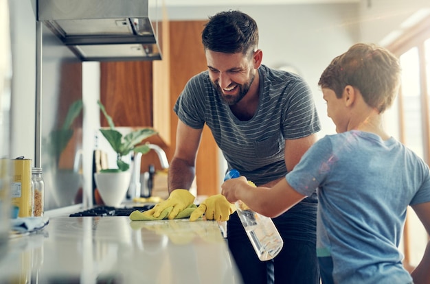 El dúo súper desinfectante de hijo y papá Fotografía de un padre y su hijo limpiando juntos la encimera de la cocina en casa