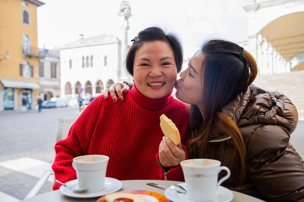 Durante o café da manhã no centro da cidade uma amiga beija a outra na bochecha