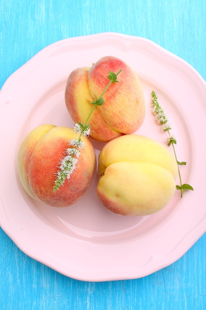 Foto duraznos maduros en un plato sobre un fondo azul.