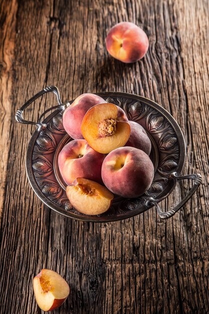 Duraznos maduros en tazón rústico y mesa de madera.