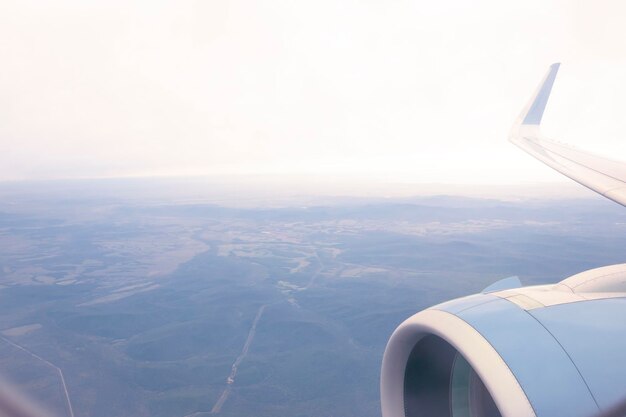 Foto durch das bullauge können sie den flügel des flugzeugs und den boden sehen. reisen sie mit der luft