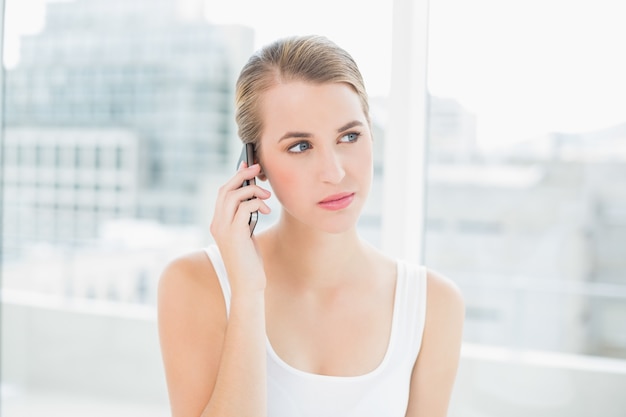 Durchdachte blonde Frau am Telefon