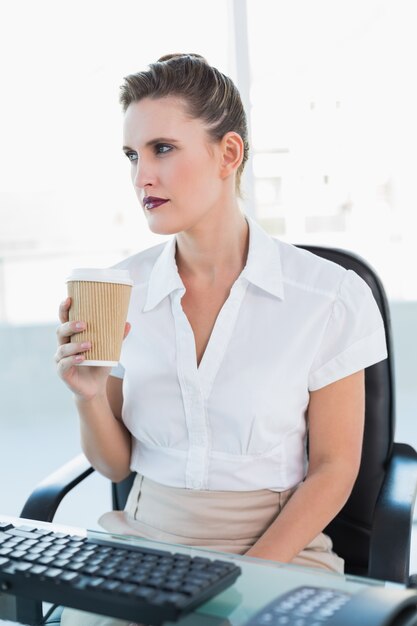 Durchdachte Geschäftsfrau, die Kaffee hält