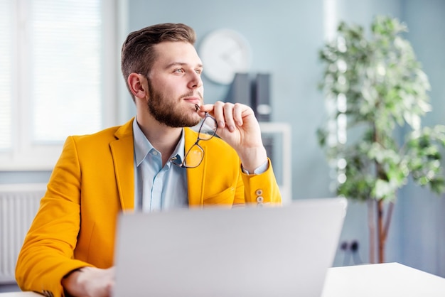 Durchdachter Arbeiter mit Laptop im Büro