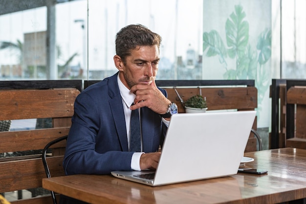 Durchdachter Geschäftsmann, der Daten auf Laptop analysiert