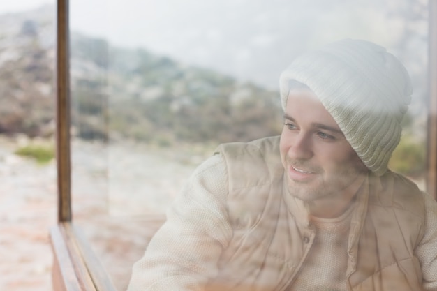 Durchdachter Mann, der heraus durch Fenster schaut