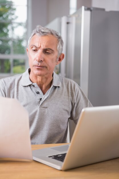 Durchdachter Mann, der seinen Laptop verwendet