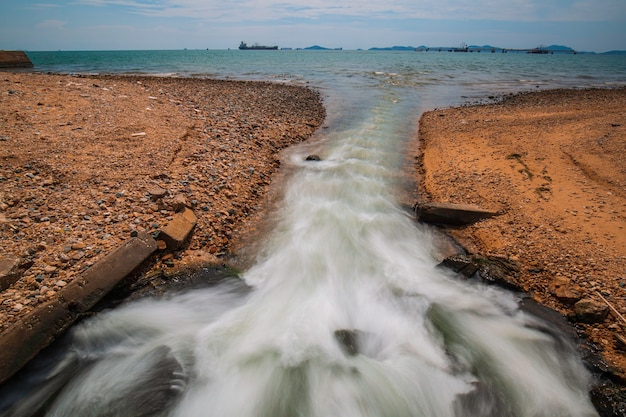 Durchlass fließendes Industriewasser in Zeitlupe ins Meer.