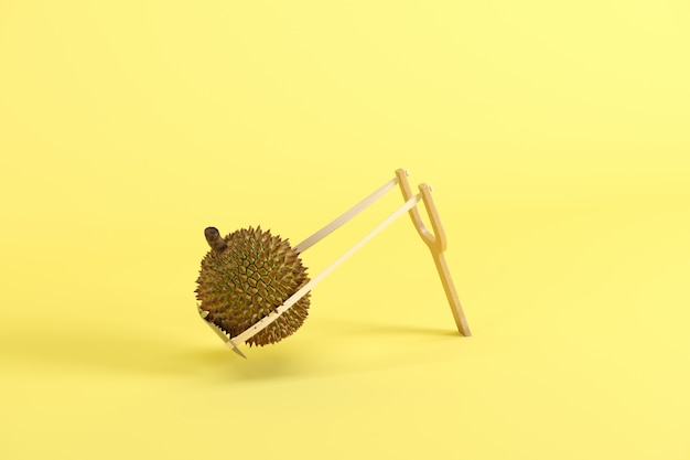 Foto durian entero en una catapulta sobre fondo amarillo