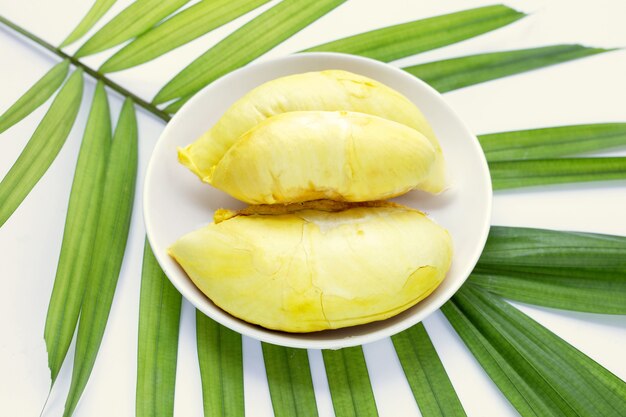 Durian in weißer Platte auf grünen Blättern