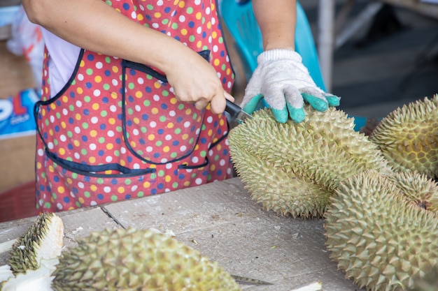 Durianverkäufer schält durian für den kunden im lokalen obstmarkt