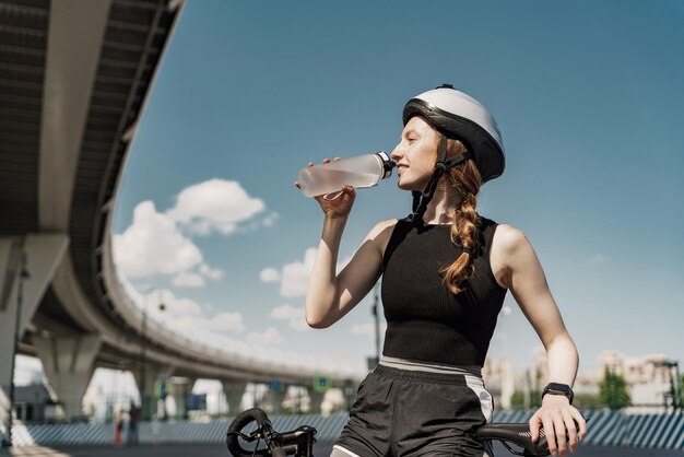 Durst ist das Trinken von reinem Wasser in einer Plastikflasche. In der Pause trainiert eine junge Frau gerne im Freien